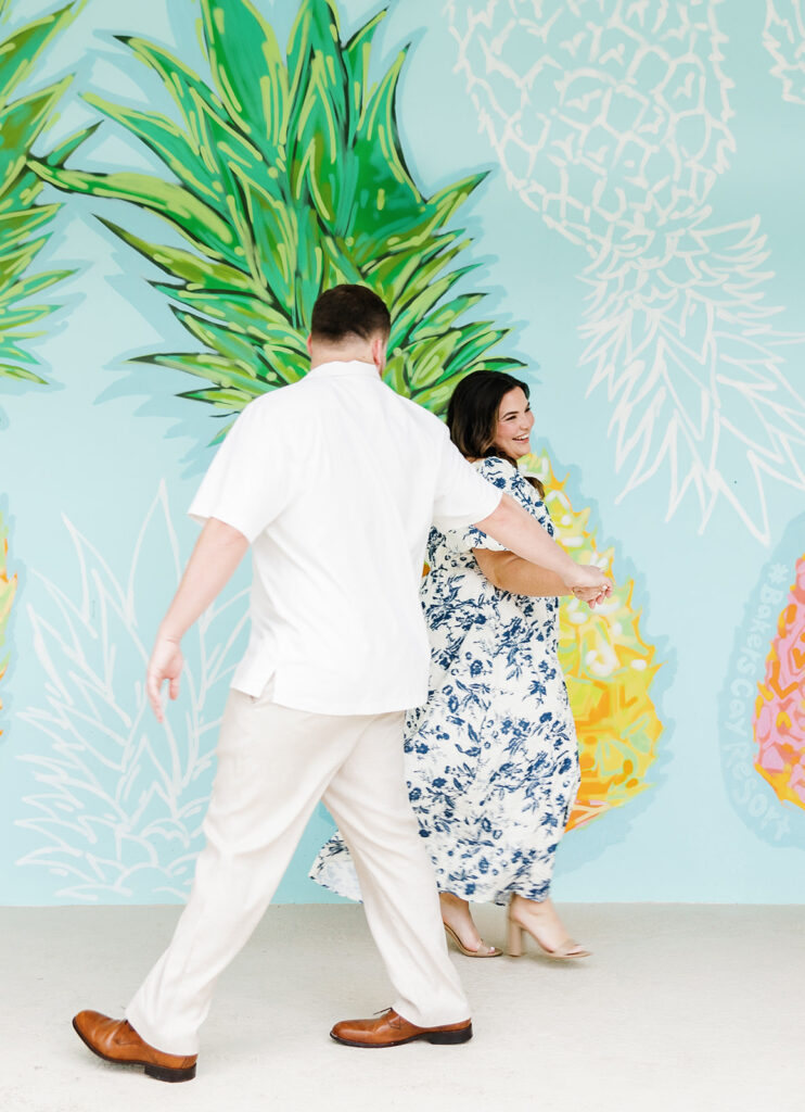 Claire and Reece laugh as they twirl in front of the vibrant mural, perfectly framed by a Key Largo wedding photographer.