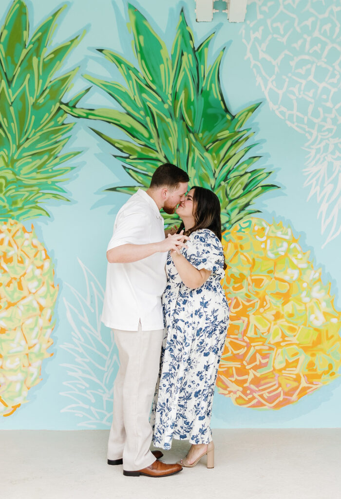 Claire and Reece share a sweet kiss in front of the colorful feature wall of the resort, captured by a Bakers Cay Resort photographer.