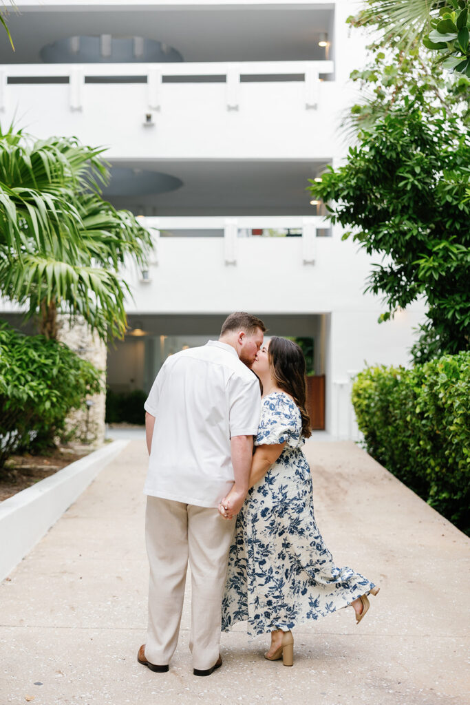 Claire and Reece share a sweet kiss along a lush, tropical walkway, beautifully captured by a destination wedding photographer.