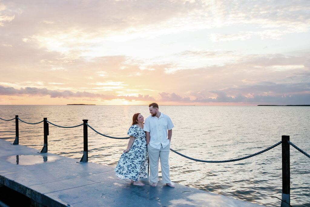 Claire and Reece walk barefoot along the dock, soaking in the breathtaking ocean views at their engagement shoot in Key Largo.