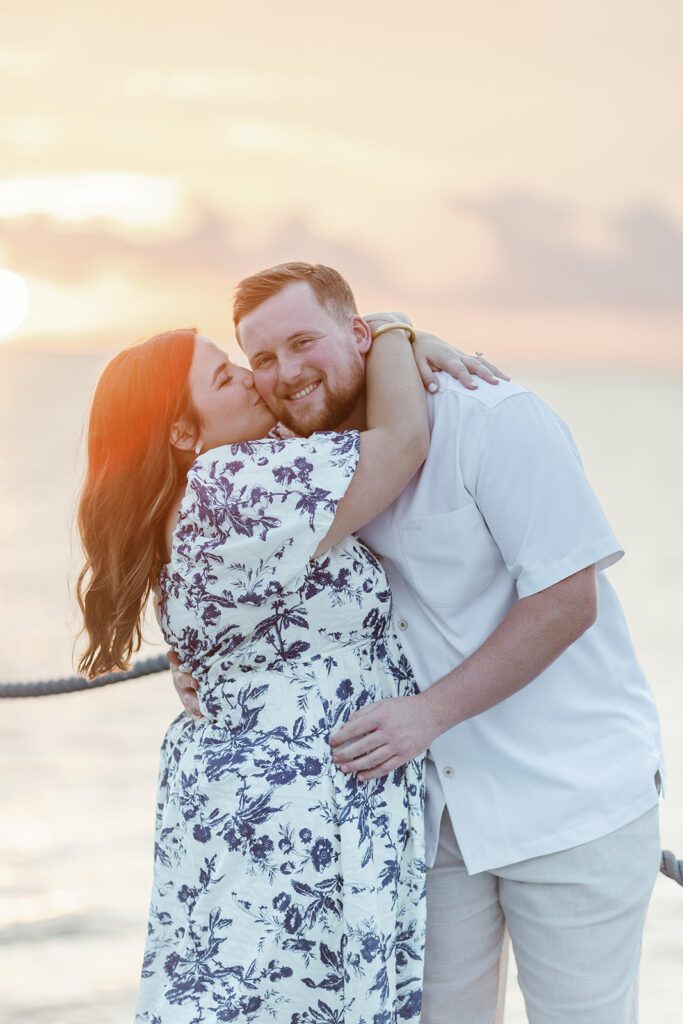 Claire kisses Reece’s cheek as the sun sets over the ocean, a beautiful moment captured by a Key Largo wedding photographer.