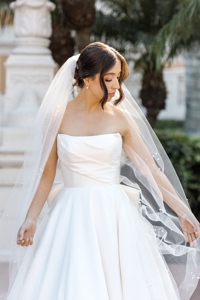 Bride Jeannie in a pearl-adorned veil, standing in the gardens of the Biltmore Hotel Coral Gables.