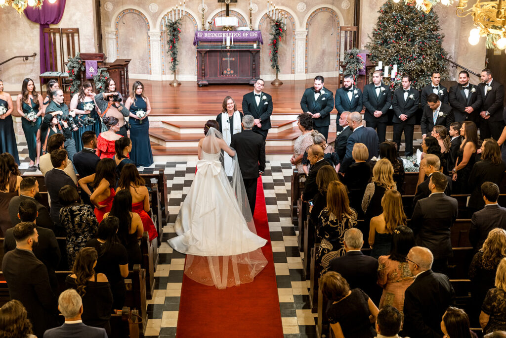 A bride and her father reach the altar, sharing an emotional moment before she is given away.