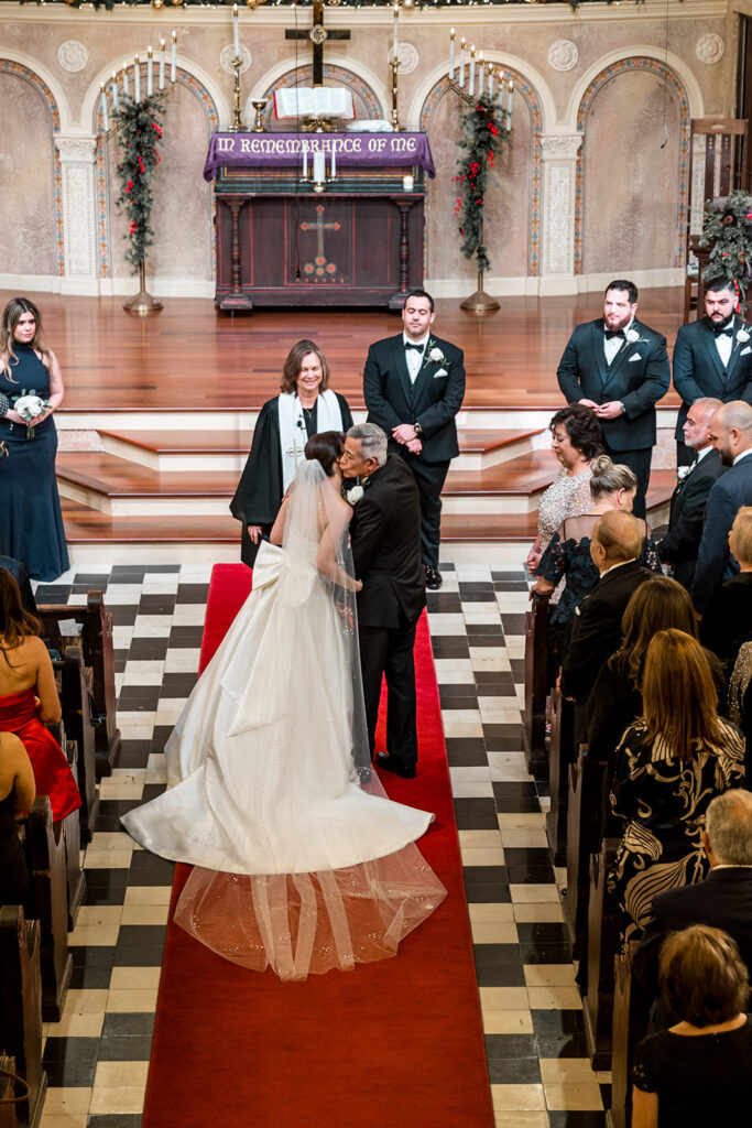 A panoramic view of a grand church wedding ceremony, with the bride, groom, officiant, and wedding party beautifully framed.