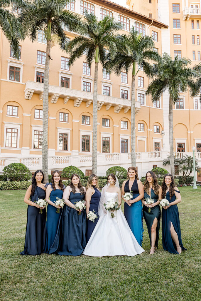 Bride and bridesmaids in navy dresses posing on the lawn of Biltmore Hotel Coral Gables.