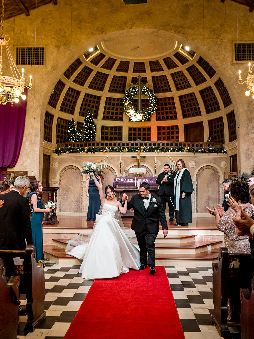 Newlyweds walking down the aisle, hand in hand, after their wedding ceremony.