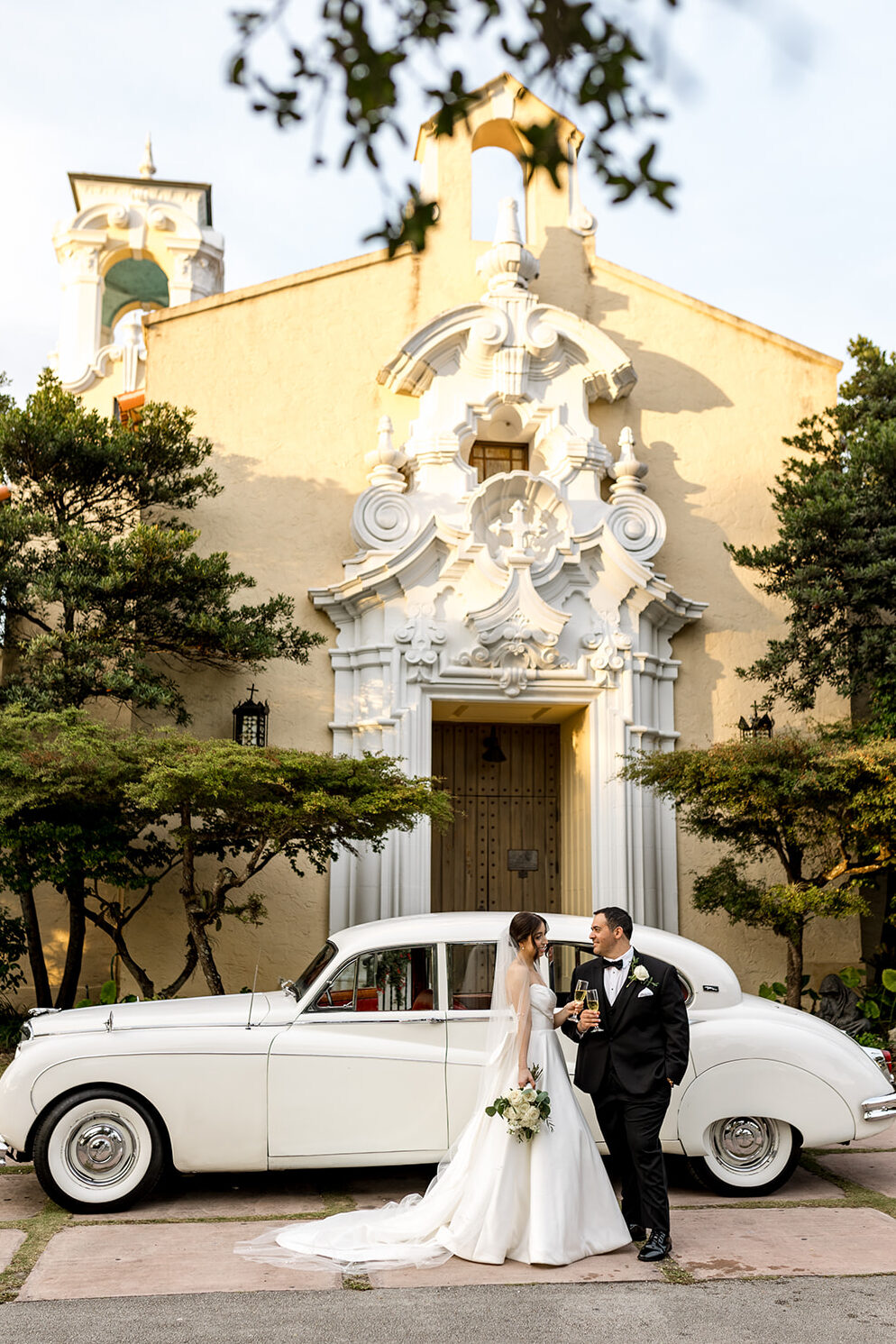 Bride and groom share a champagne toast in front of their wedding car at Biltmore Hotel Coral Gables.