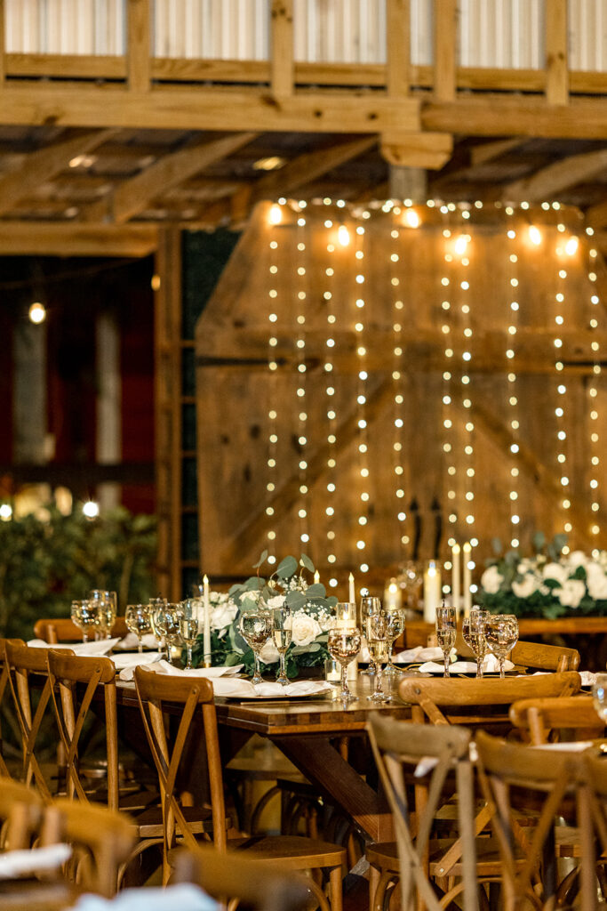 Wedding reception table with candles and floral arrangements at a rustic venue.