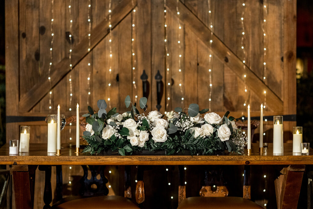 Elegant sweetheart table with floral arrangement and candlelight at a wedding reception.