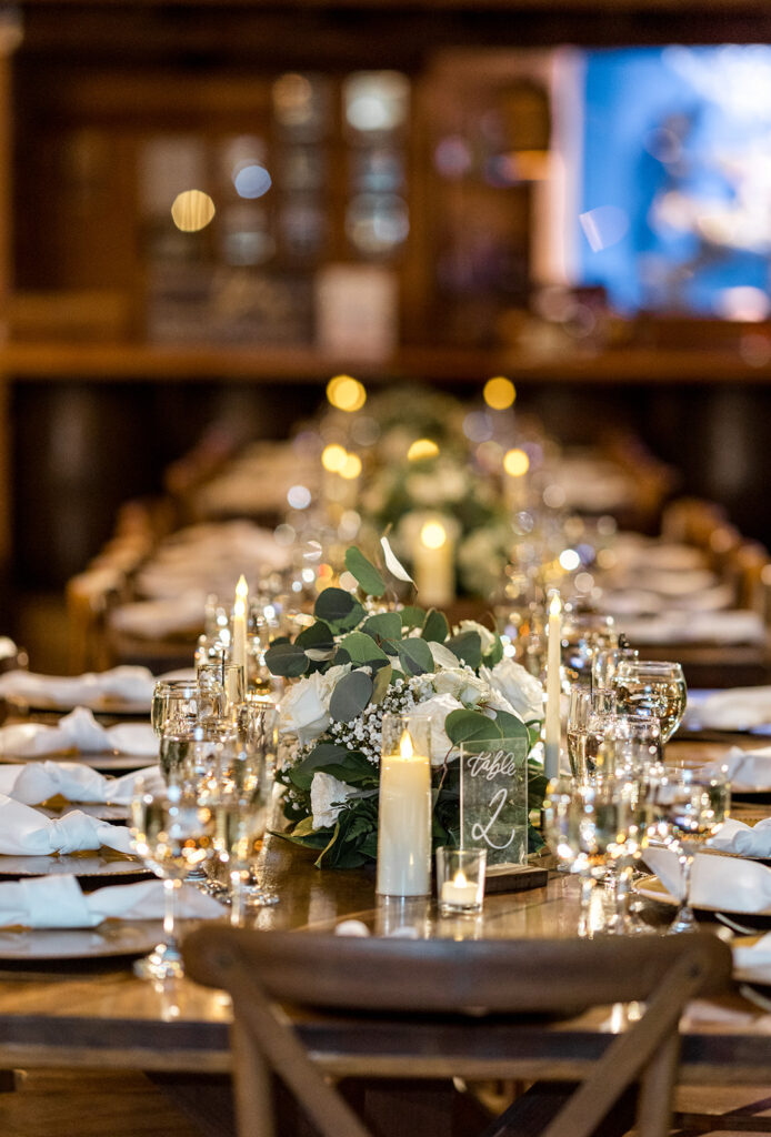 Wedding reception tables decorated with candles, floral centerpieces, and glassware.