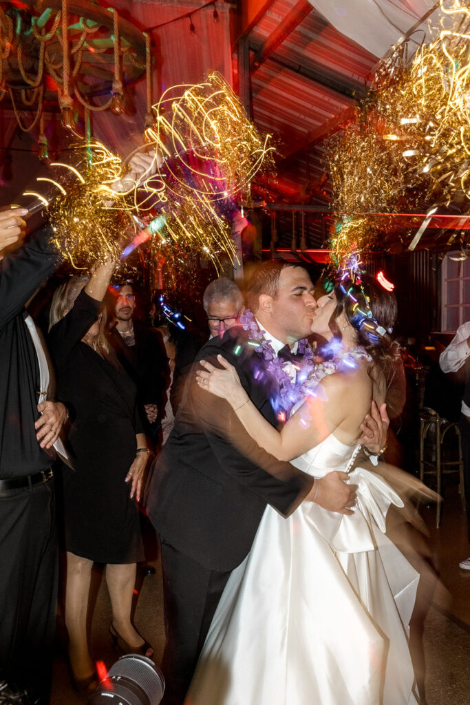 Jeannie and Carlos share a romantic kiss under a tunnel of golden sparklers during their wedding exit at Biltmore Hotel Coral Gables.