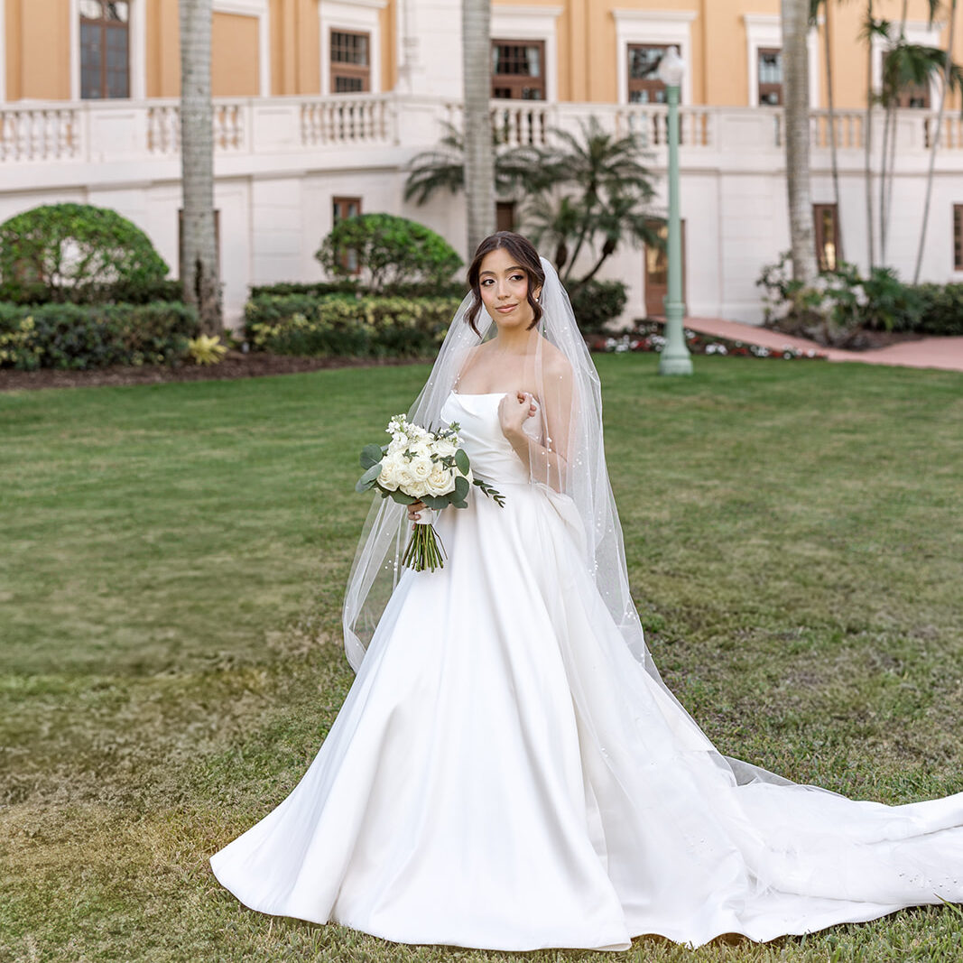 Jeannie stuns in her wedding gown, posing in front of the palm-lined Biltmore Hotel Coral Gables.