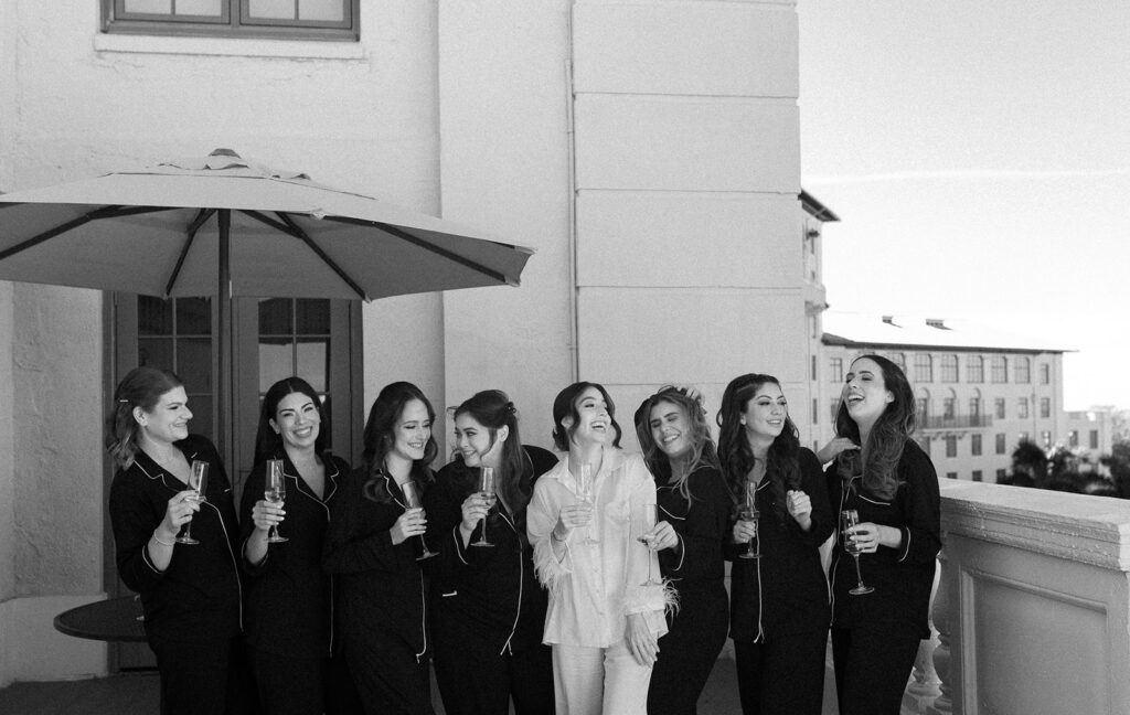 A candid black-and-white shot of Jeannie and her bridesmaids laughing with champagne at the Biltmore Hotel Coral Gables.