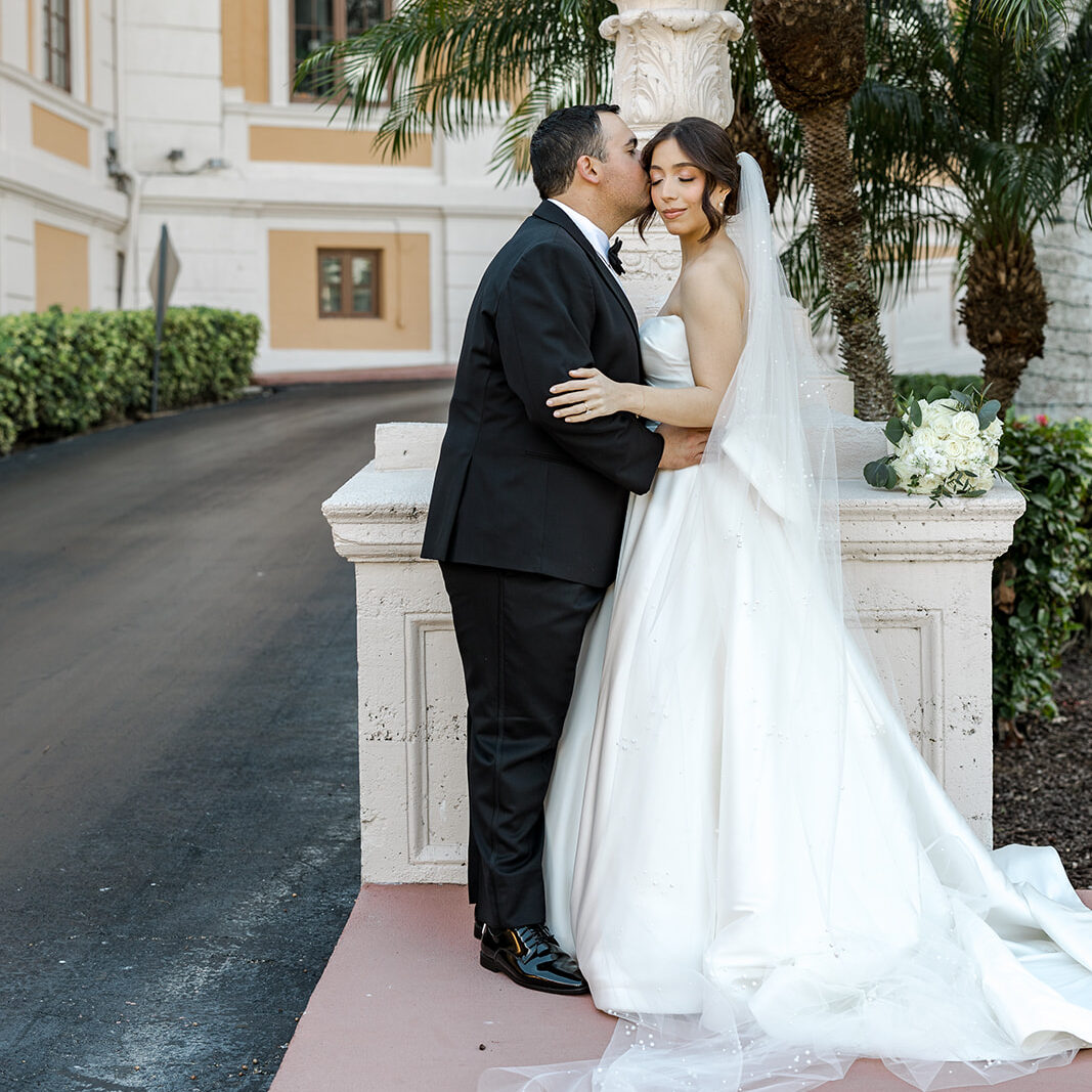 Groom Carlos kisses Jeannie’s cheek in a romantic portrait at the Biltmore Hotel Coral Gables.