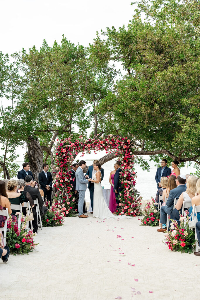 Rebecca and Graysen exchange vows under the floral arch, witnessed by their families and closest friends. Captured by Claudia Amalia, a destination wedding photographer.