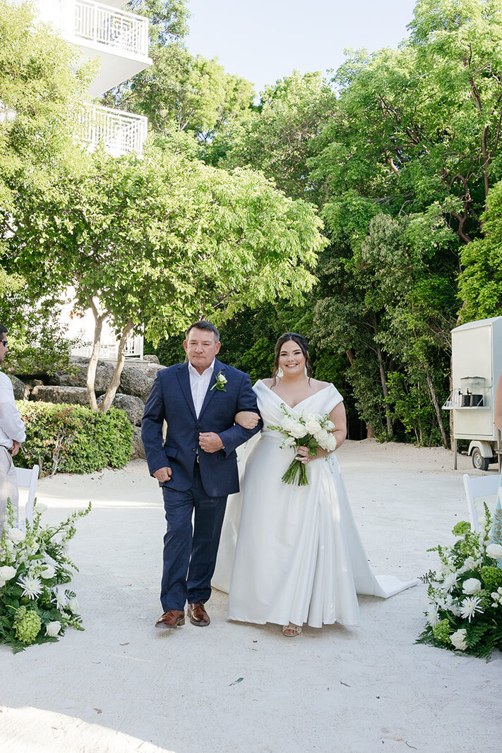 The beautiful bride, Claire, on the arm of her father as they walk down the wedding aisle in Baker's Cay resort. Captured by Claudia Amalia.