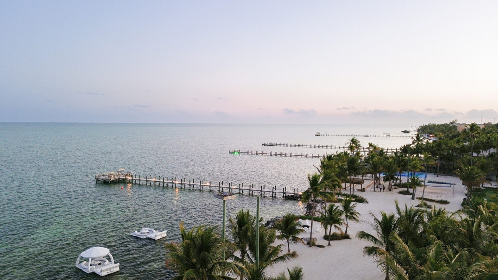 Wide aerial view of a beachfront resort with multiple docks and clear water for Florida Keys weddings.