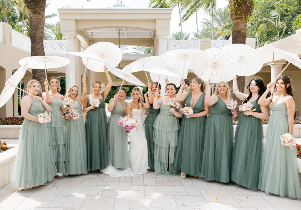 Bride and bridesmaids in sage green posing with parasols for a sunny Florida Keys weddings portrait.