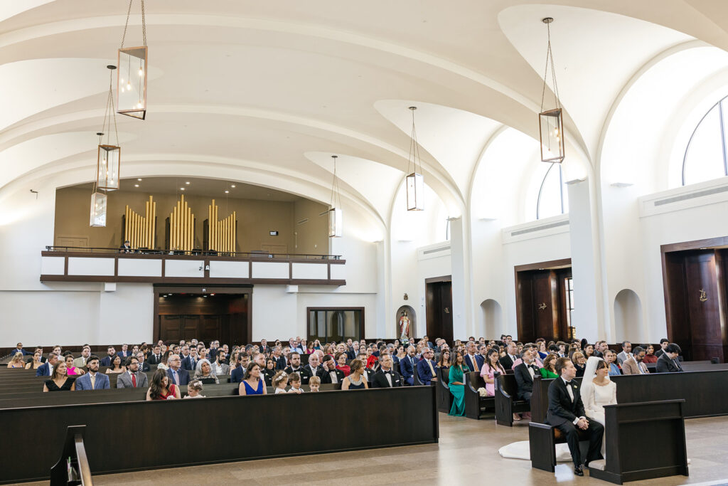Wedding guests sitting in pews in a bright, modern chapel for a city wedding ceremony.