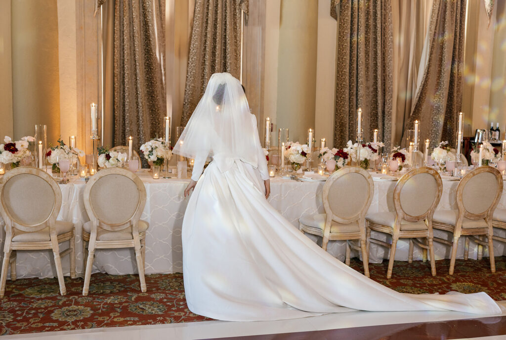 Bride with a long train walking down a formal aisle at a high-end city wedding reception.