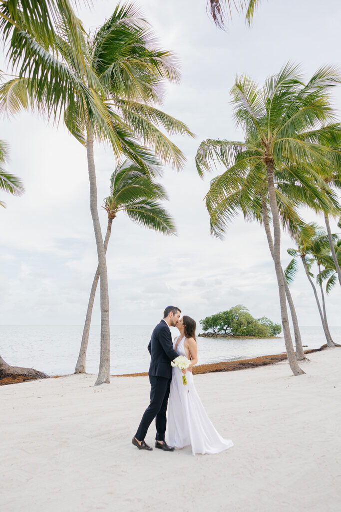Bride and groom portrait on a sandy beach lined with palms for a Key Largo weddings celebration.