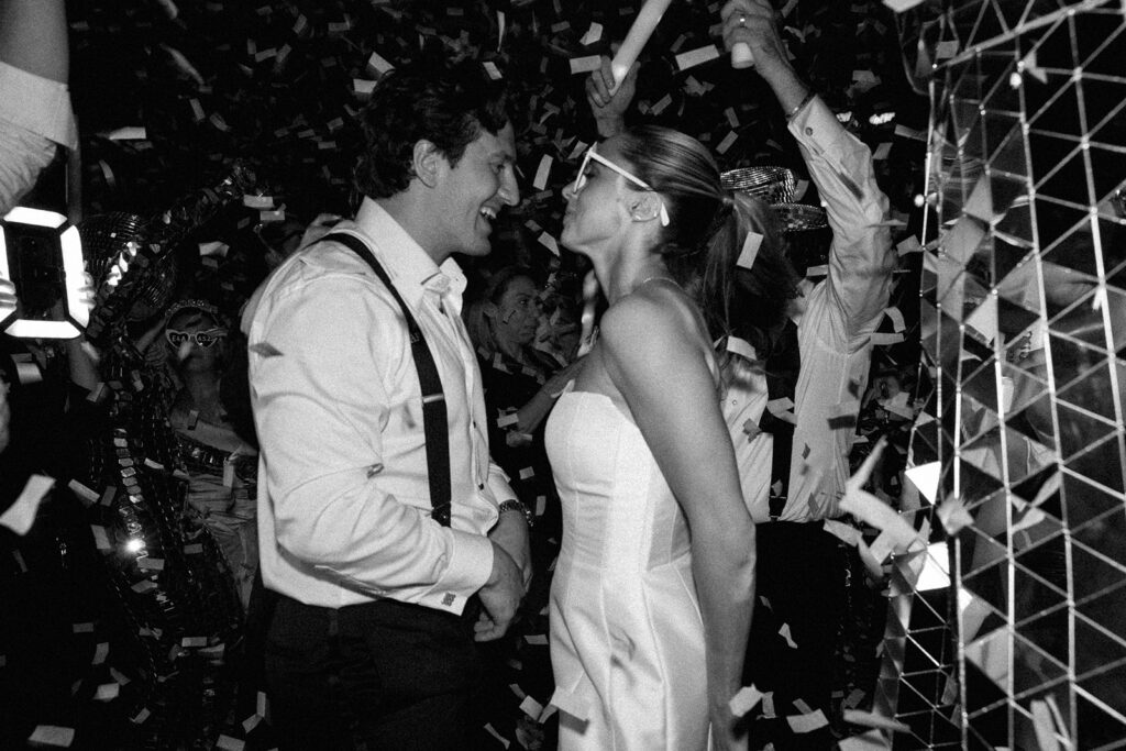 Black and white photo of a couple celebrating with confetti during their high-energy Miami city weddings reception.
