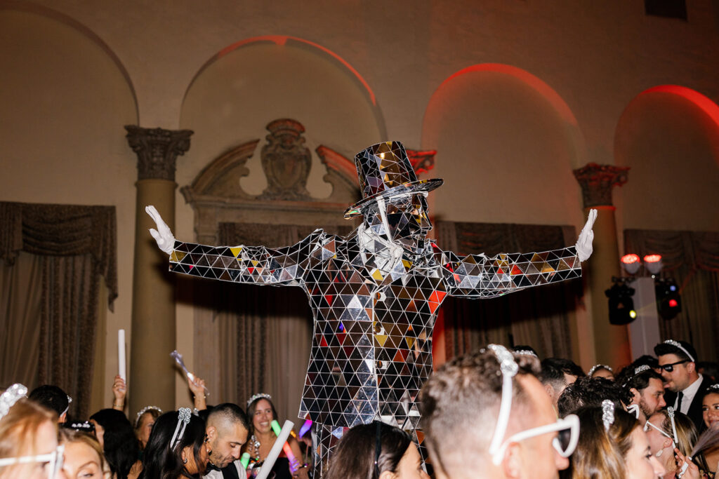 Mirrored party entertainer leading a dance at a grand city wedding reception.