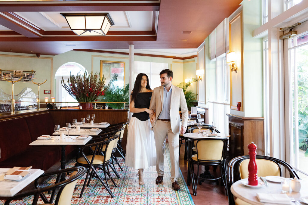 Stylish couple walking through a hotel dining area for a Miami weddings portrait.
