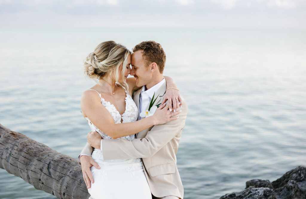 Intimate portrait of couple embracing on the ocean rocks by their Florida Keys wedding photographer.